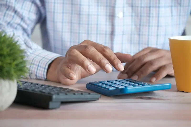 Calculadora e contas em papel sobre a mesa, como quem confere se o ISS foi descontado da nota fiscal do MEI