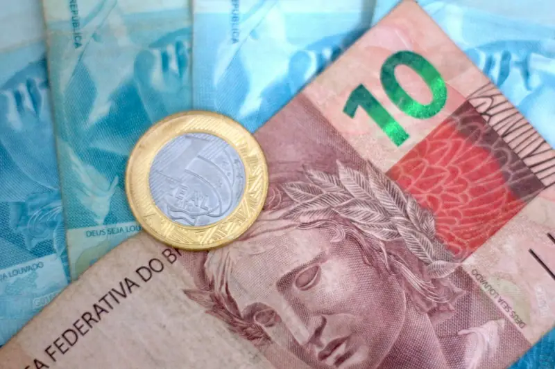 Moedas e notas pequenas de real espalhadas sobre uma mesa, como o troco de uma venda de valor baixo